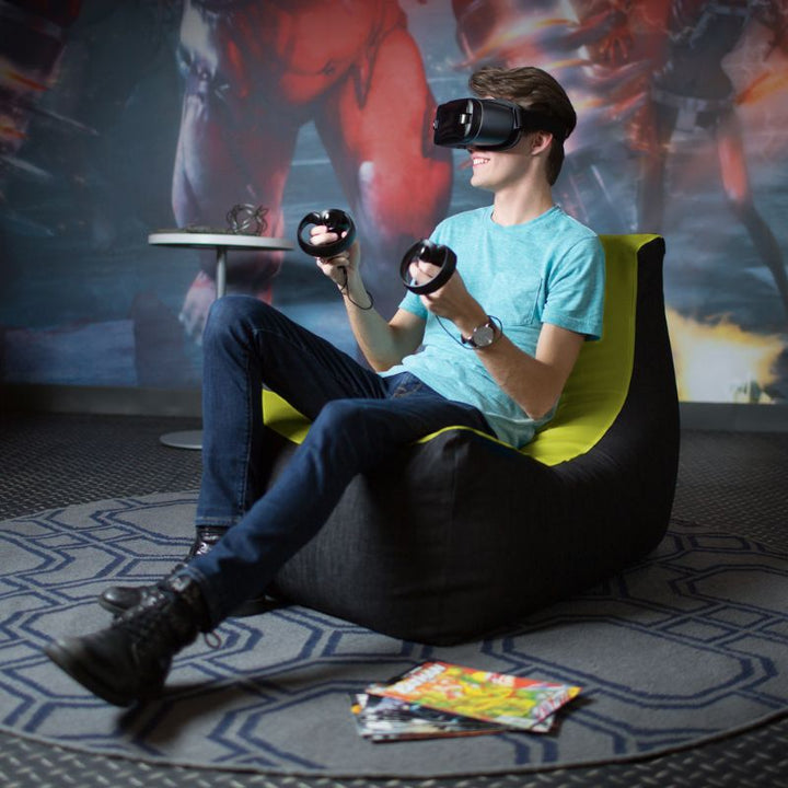 A teen uses a VR headset while seated in the Jaxx Pixel gaming bean bag chair in green, a comfortable low seat for gaming