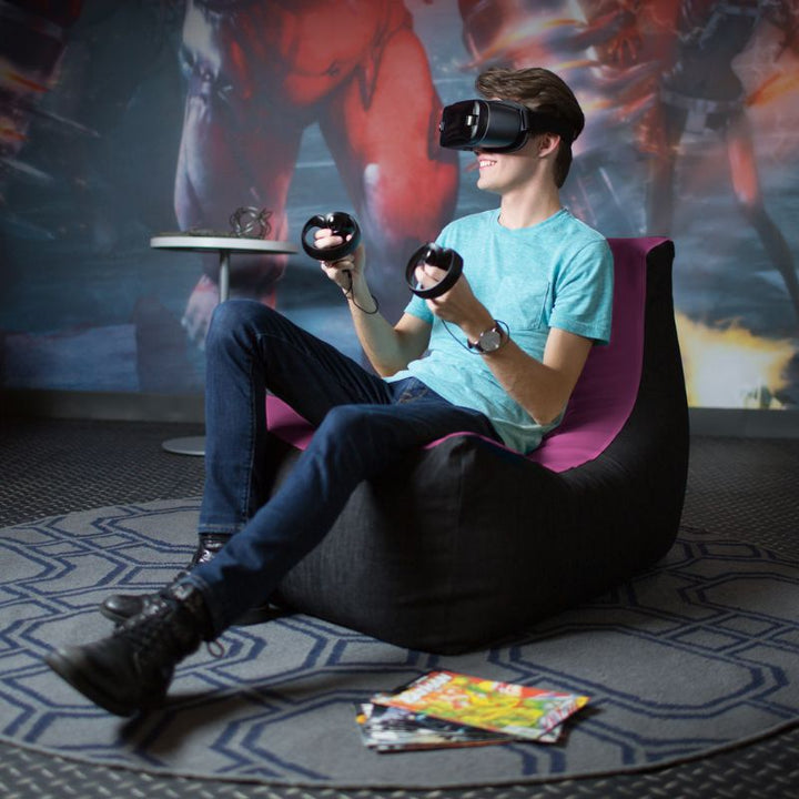 A teen uses a VR headset while seated in the Jaxx Pixel gaming bean bag chair in purple, a supportive gaming seat for kids