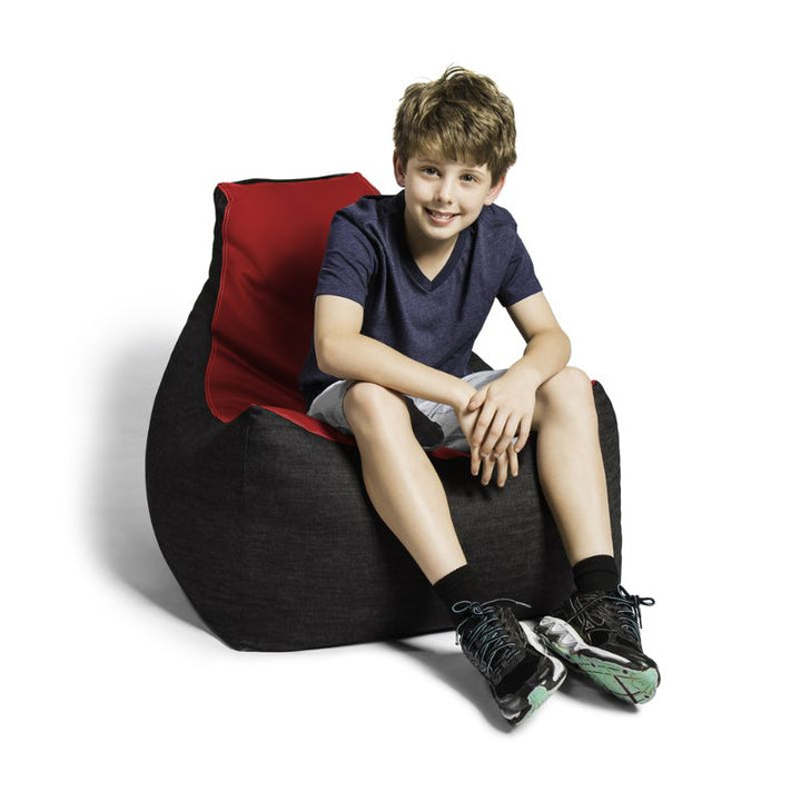 A boy sits comfortably in the Jaxx Pixel gaming bean bag chair in red, a supportive seat for kids' game rooms