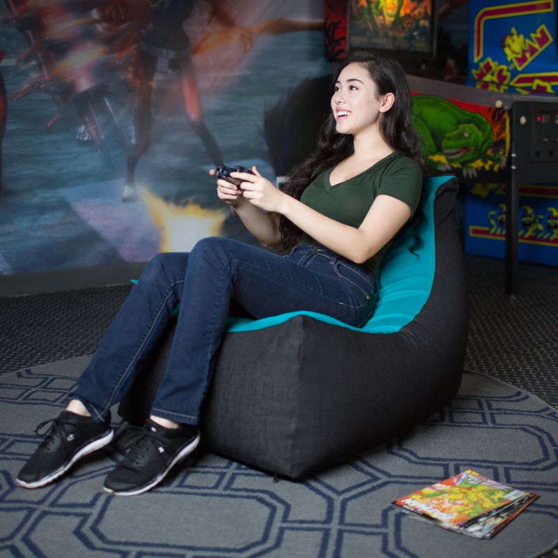 A teen relaxes in the Jaxx Pixel gaming bean bag chair in teal while playing video games, sensory seating for kids