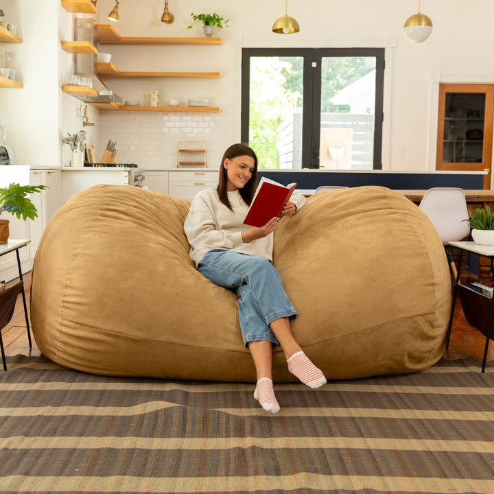 Woman reading on the Jaxx giant bean bag chair in camel microsuede in a styled living space