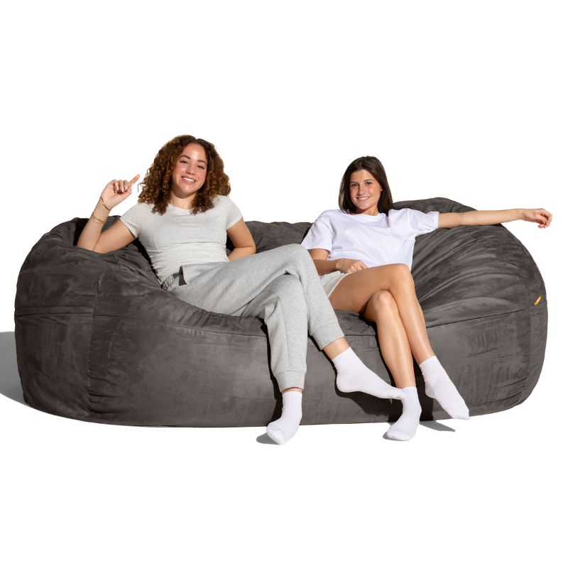 Two people seated on the Jaxx 7 ft giant bean bag chair in charcoal microsuede, oversized seating for sensory and living spaces