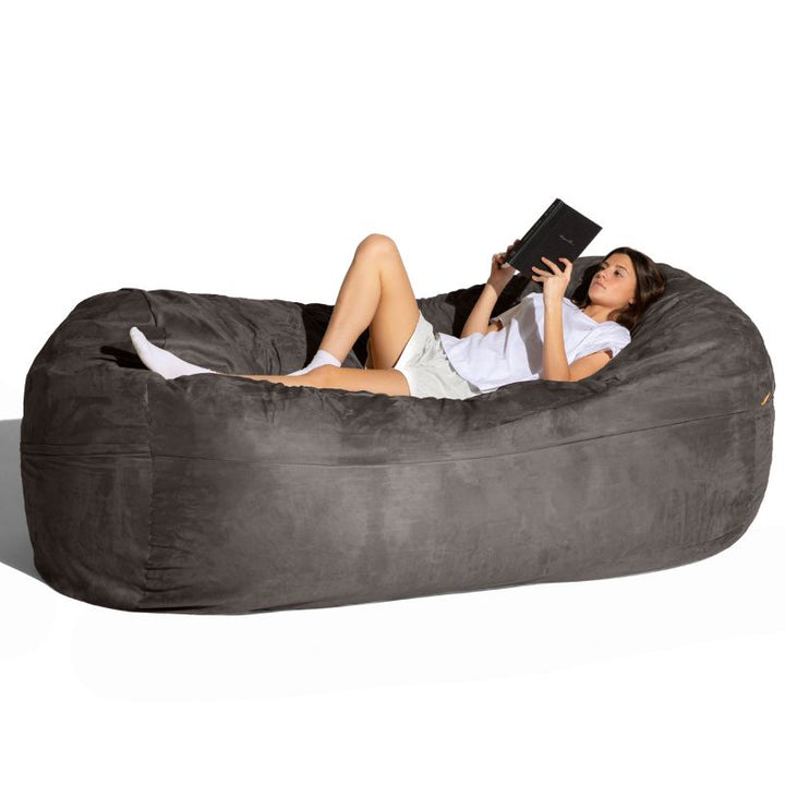 Woman reading on the Jaxx 7 ft giant bean bag chair in charcoal microsuede, seating for sensory and living spaces