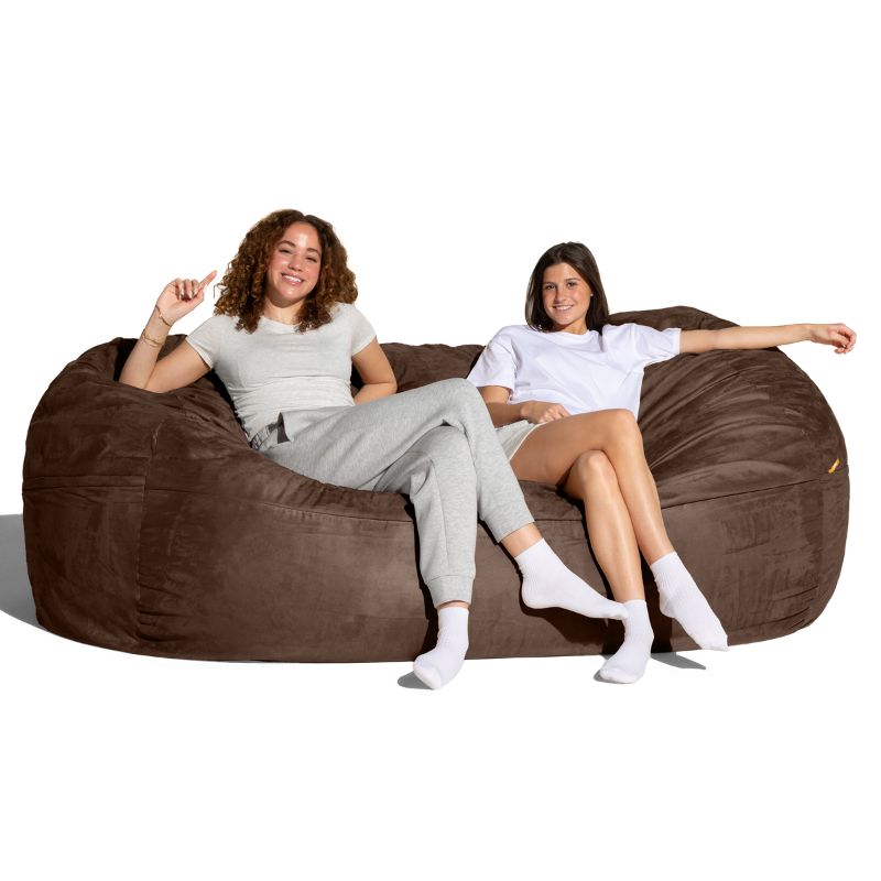 Two people relaxing on the Jaxx giant bean bag chair in chocolate microsuede for calm corners and family rooms