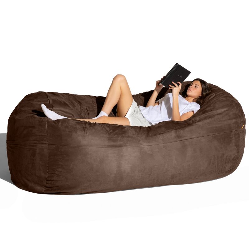 Woman reading on the Jaxx giant bean bag chair in chocolate microsuede for calm corners and family rooms