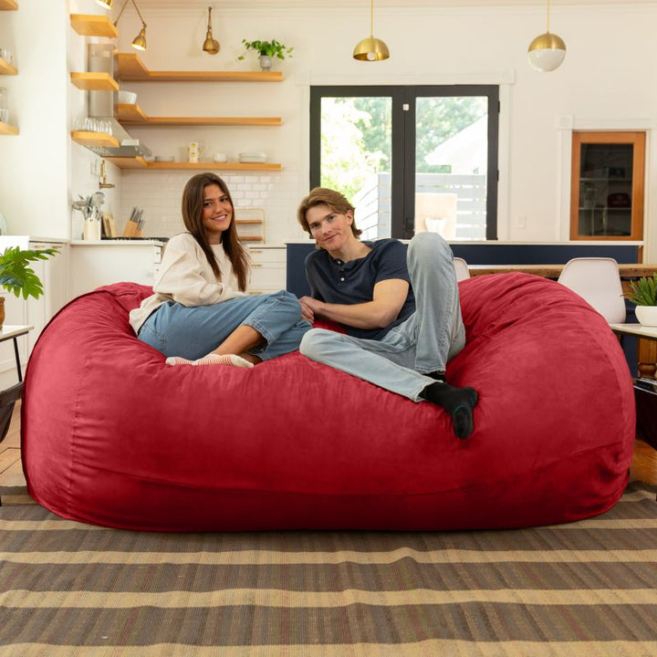 Couple relaxing together on the Jaxx 7 ft giant bean bag chair in cinnabar microsuede in a styled living space