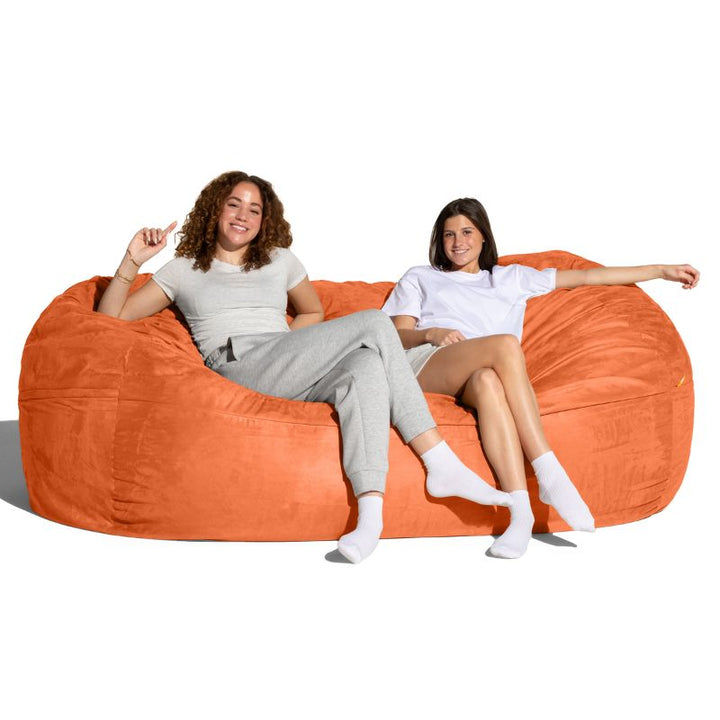 Two people seated on the Jaxx giant bean bag chair in mandarin microsuede for family and sensory spaces