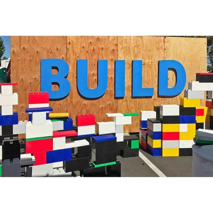 An outdoor structure built from EverBlock giant building blocks for kids beneath a large BUILD sign, demonstrating STEM building in action