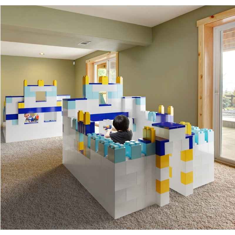 A child playing inside a walk-in fort built from the EverBlock Large Starter Kit, showing giant modular building blocks used for gross motor play at home