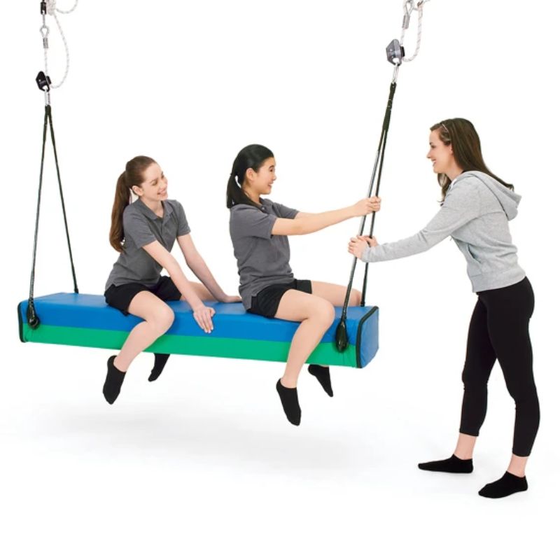 Two riders share the Southpaw Glider Bolster Swing in the standard size while a therapist guides its smooth vestibular gliding motion