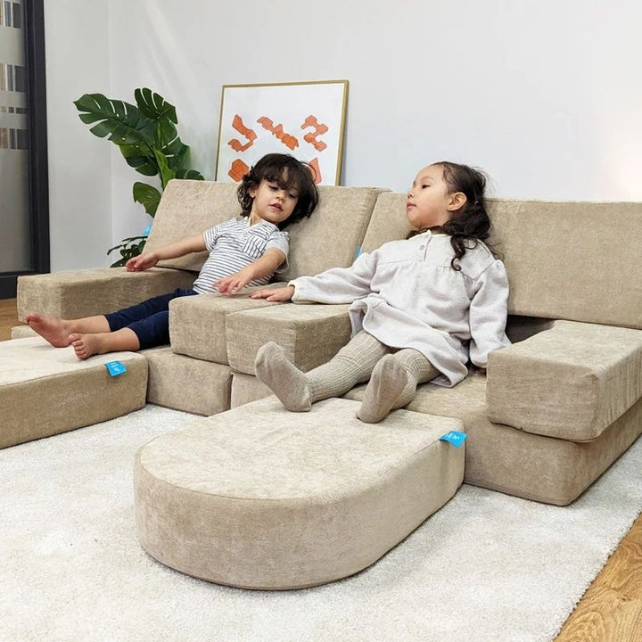 Two children actively playing and building with the Go Coconut Builder Bundle, demonstrating the fort and enclosed space configurations made possible by the 7-piece modular foam play couch with walls and doors