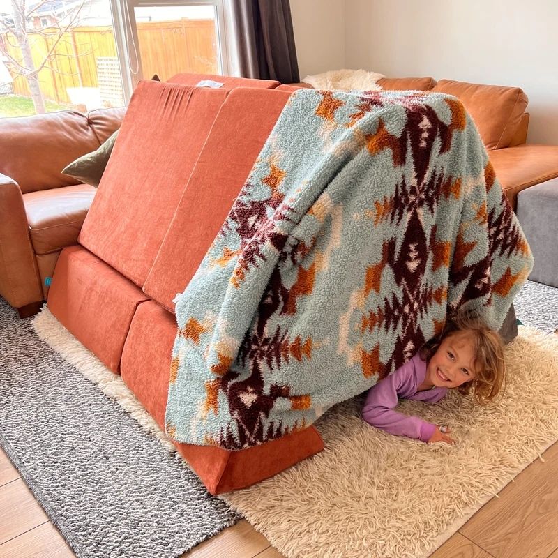 Child actively playing on Go Coconut - The Coconut in Orange shown in an indoor setting demonstrating the Montessori-inspired open-ended creative and sensory play of the Canadian-made modular play couch