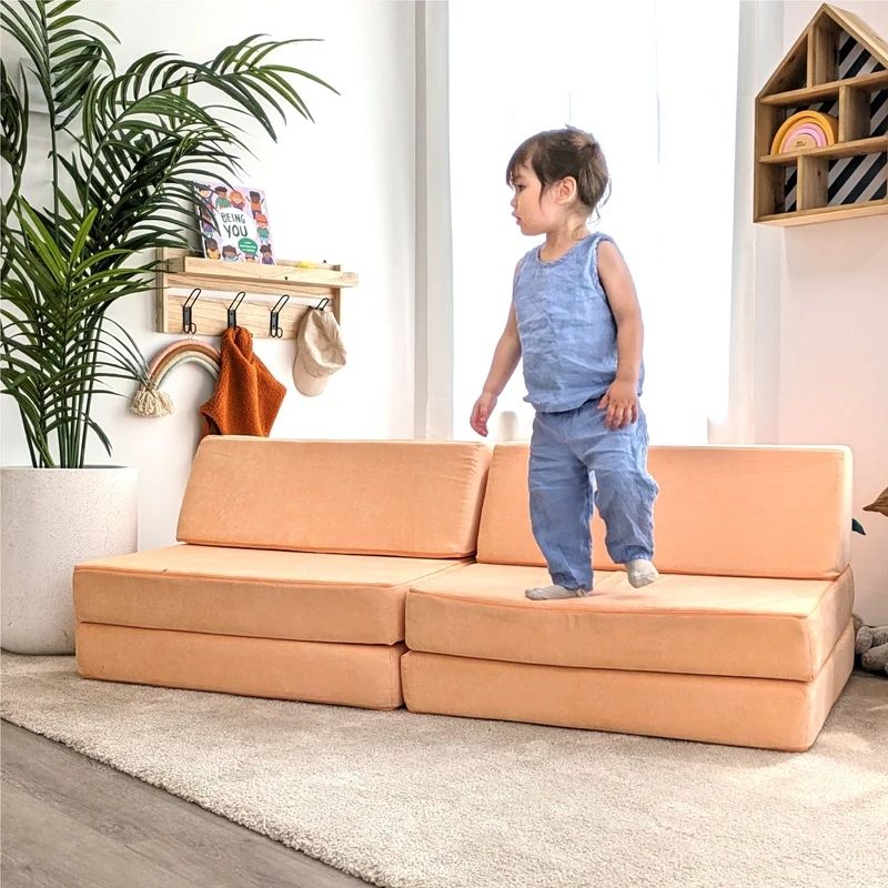 Child actively playing on Go Coconut - The Coconut in Peach Party demonstrating the creative modular building configurations and sensory play value of the Montessori-inspired Canadian-made play couch
