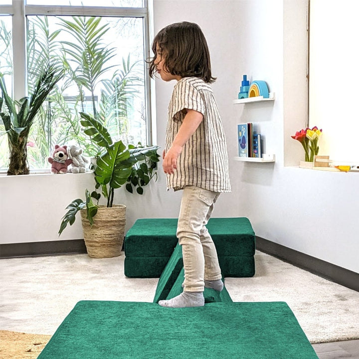 Child actively playing on the Go Coconut Half Coconut in Forest Fern, showing vestibular and gross motor sensory play from the side