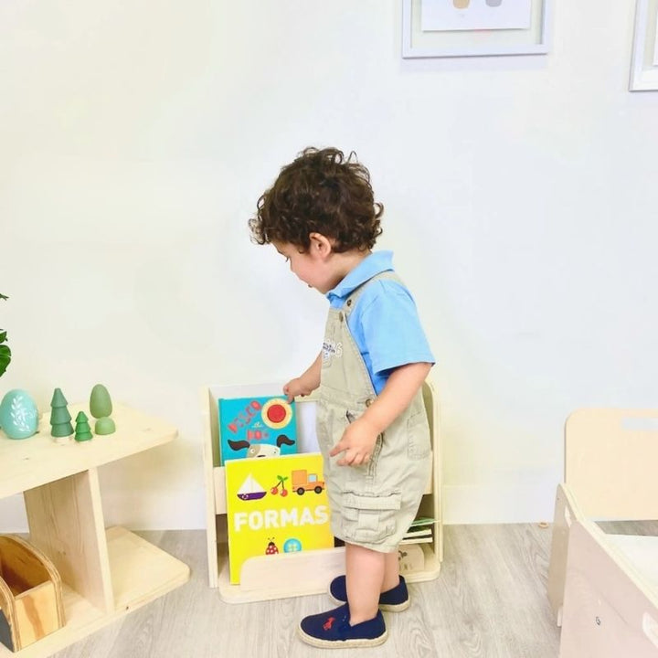 Boy independently selecting a book from the Sapiens Child Guava Montessori Bookshelf, demonstrating the forward-facing design that supports independent reading and early literacy development