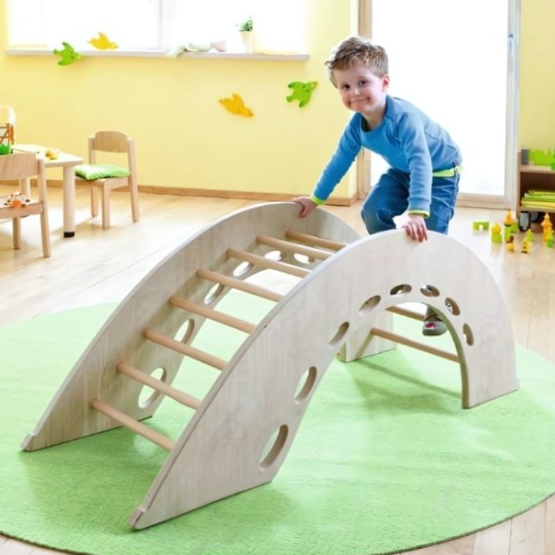 HABA Pro Climbing Arch showing a child climbing over the solid birch wood arch, demonstrating active gross motor play