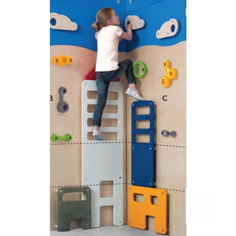 Child climbing the HABA Pro City Wall bouldering panel, with close-up view of the varied grip shapes, sizes, and birch wood skyscraper applications used for indoor gross motor development