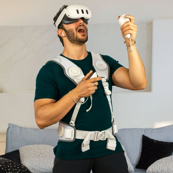 Player using a VR headset and controller at home while wearing the white Woojer Vest 4 haptic vest Made for Meta edition for immersive VR play