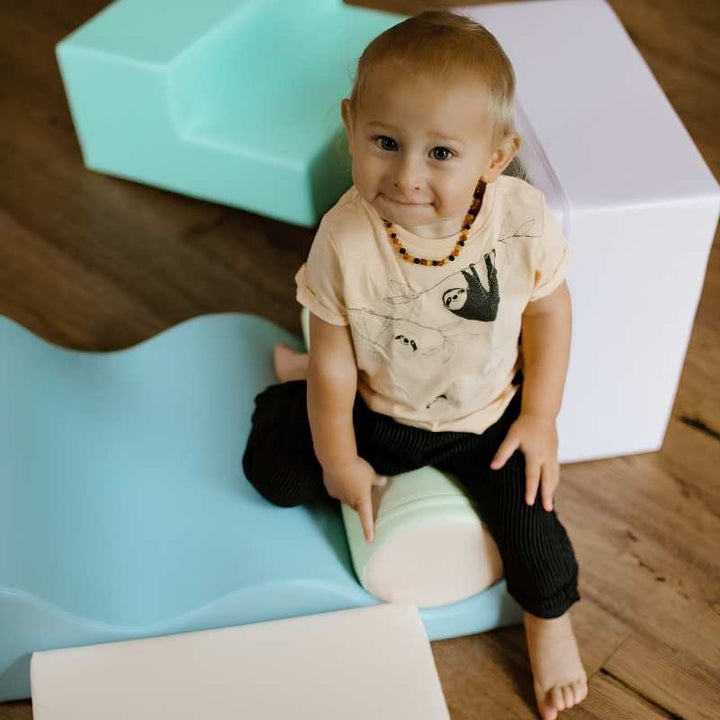 Toddler boy sitting among the foam shapes of the IGLU Explorer Soft Play Set in a pastel colourway