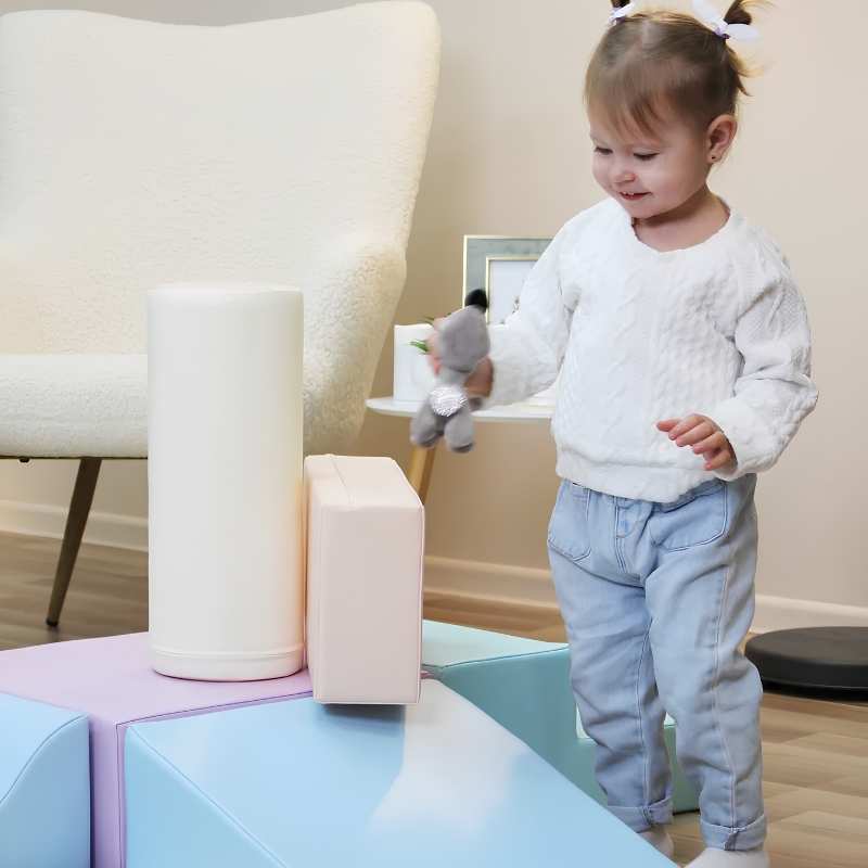 Toddler girl playing with the foam cylinder from the IGLU Explorer Soft Play Set in a pastel colourway