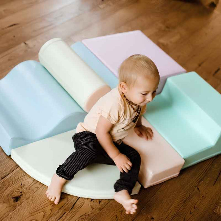 Toddler crawling onto the quarter-round shape of the IGLU Explorer Soft Play Set in a pastel colourway