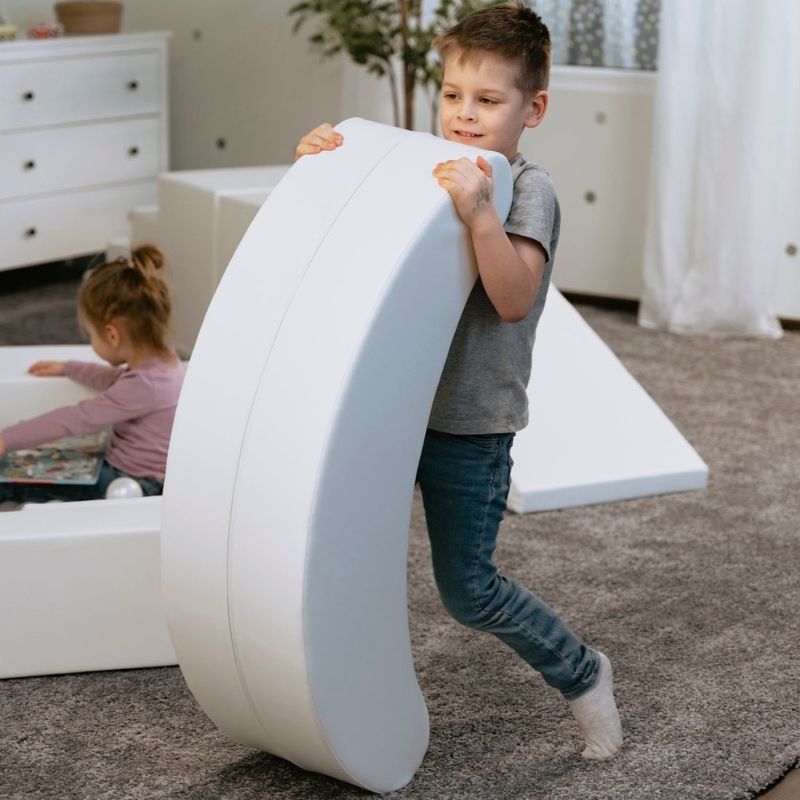 Boy rocking on the IGLU Banana Rocker from the Soft Play Party Set, foam rocker supporting balance and vestibular sensory input