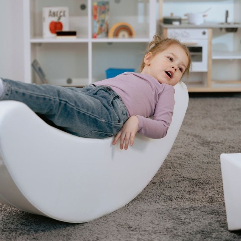 Child playing on the IGLU Banana Rocker, a foam rocking piece from the IGLU Soft Play Party Set supporting vestibular development