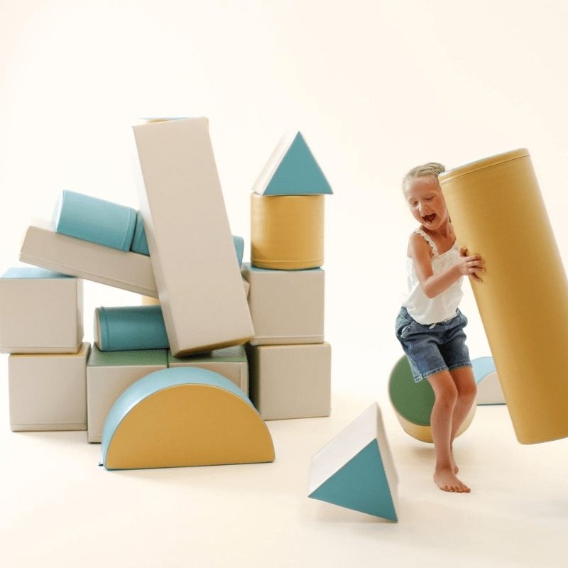 Young girl lifting an IGLU Soft Play foam block, showing the lightweight design that allows children to rearrange the Fortress Set independently