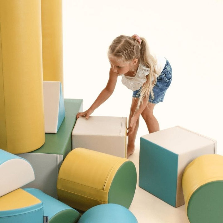 Girl playing on the IGLU Soft Play Fortress Set in turquoise, demonstrating how foam climbing blocks support imaginative and physical development
