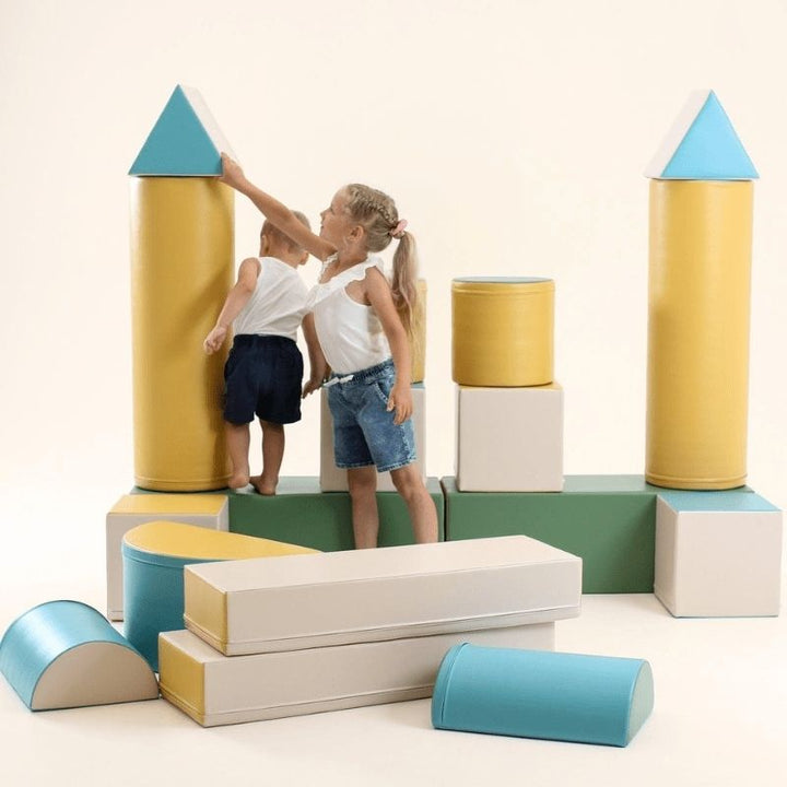 Two children exploring the IGLU Soft Play Fortress Set in pastel turquoise, using foam climbing blocks to build and climb indoors