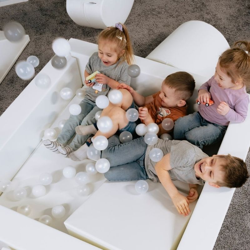 Top-down view of children actively playing across the IGLU Soft Play Party Set, showing full layout of the foam climbing set