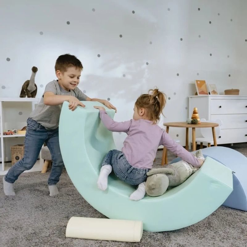 Two children climbing and playing on the IGLU Montessori Soft Play Rainbow set, showing gross motor skills development