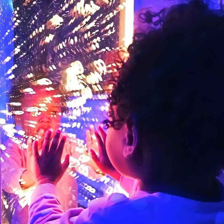 Two children press their hands against the TFH Infinity Bubble Wall, seeing their reflections multiplied among the rising bubbles