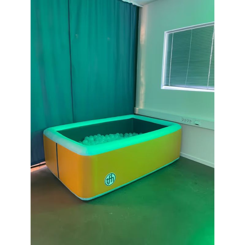 TFH Heavy Duty Inflatable Ball Pool set up in a multi-sensory room, shown with ambient lighting to highlight the pool's sturdy inflatable design