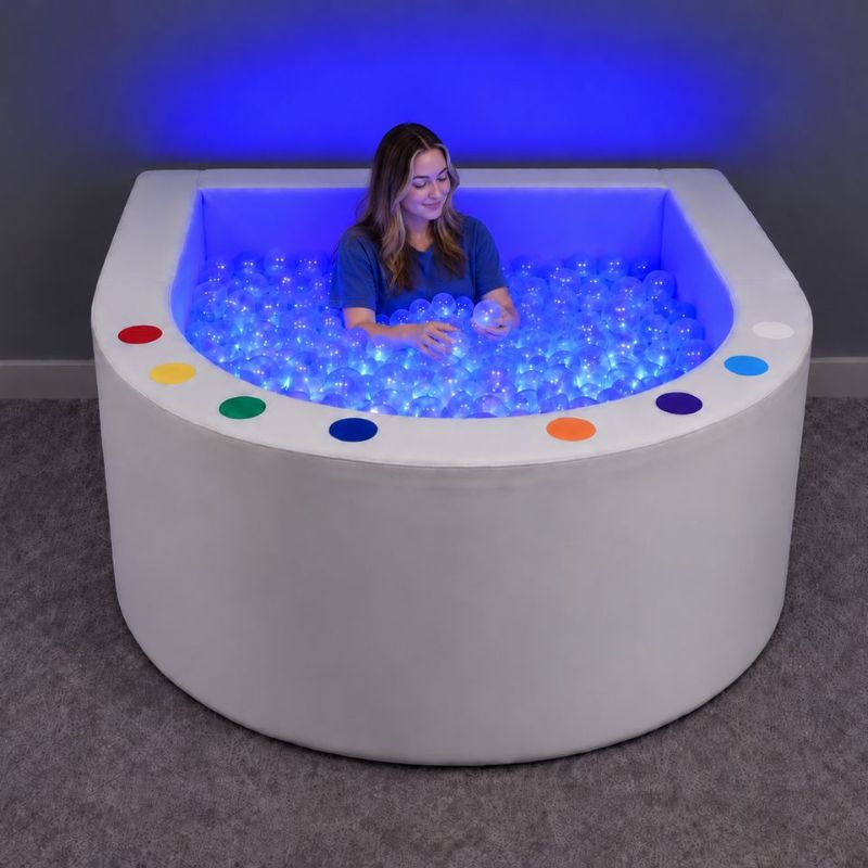 Adult relaxing among glowing clear balls in the Experia Interactive LED Ball Pool, an illuminated ball pool for all ages
