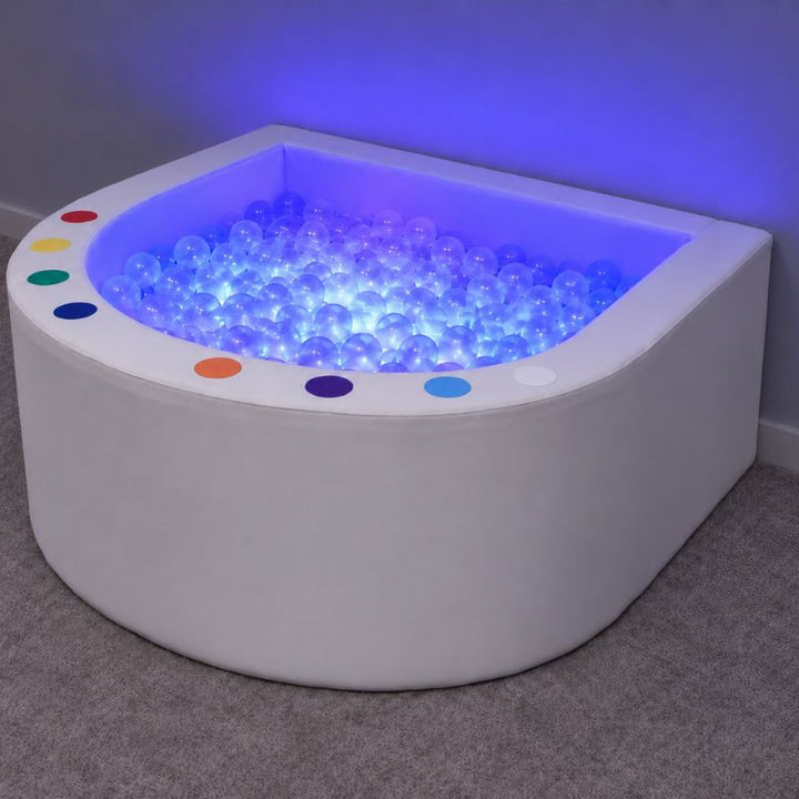 Experia Interactive LED Ball Pool glowing blue, with eight colored switches around its curved soft walls, ready for a multi-sensory room
