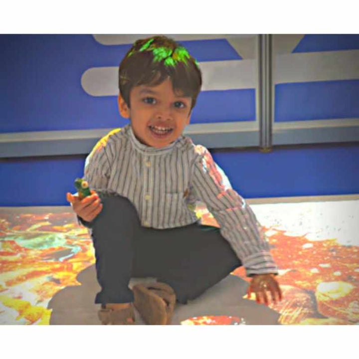 Child engaging with a Budii interactive sensory projector floor activity, a colourful motion-responsive play scene