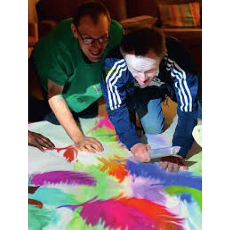 Budii interactive sensory projector feather-themed floor activity, an adult and teen sharing a motion-activated sensory game