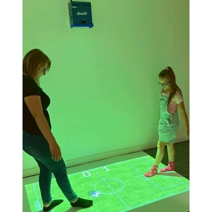 Budii interactive sensory projector floor game in use, an adult and child playing a motion-activated soccer activity