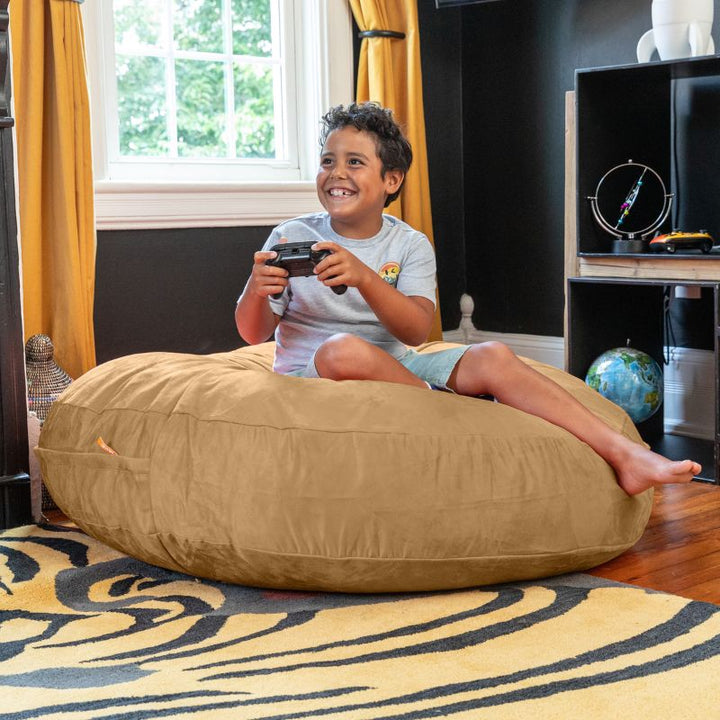 A boy playing video games on a camel Jaxx Cocoon 4ft kids bean bag chair, a comfortable sensory crash pad