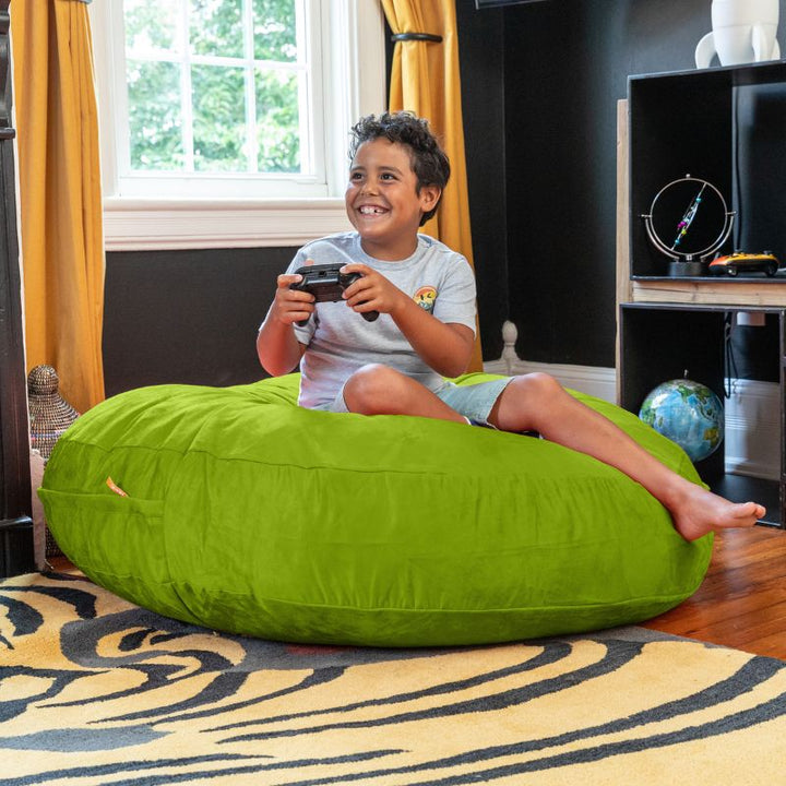 A boy playing video games on a lime Jaxx Cocoon 4ft kids bean bag chair, a playful deep pressure crash pad