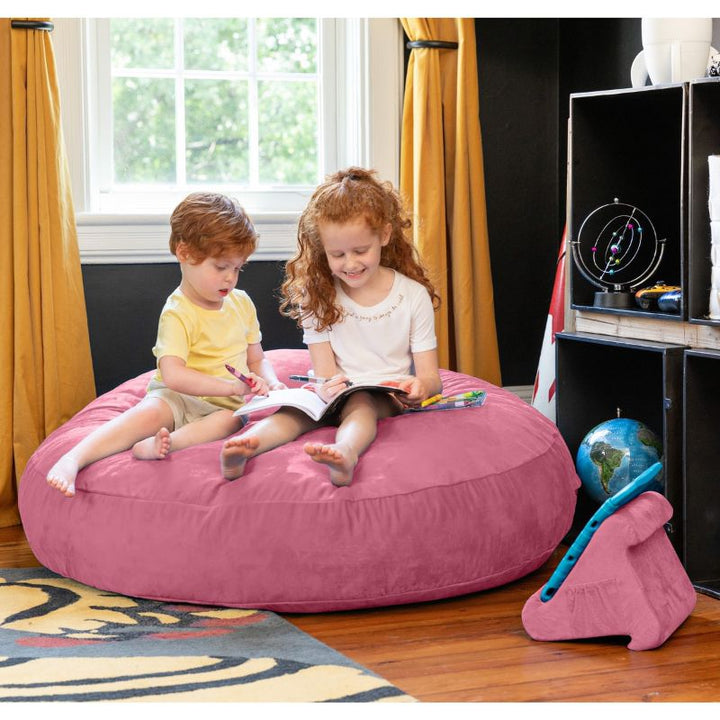 Two children reading together on a pink Jaxx Cocoon 4ft kids bean bag chair, a soft sensory seat for kids' rooms