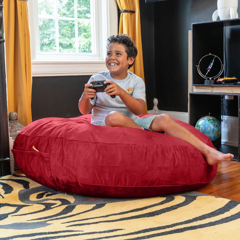 A boy playing video games on a red Jaxx Cocoon 4ft kids bean bag chair, a bold sensory crash pad