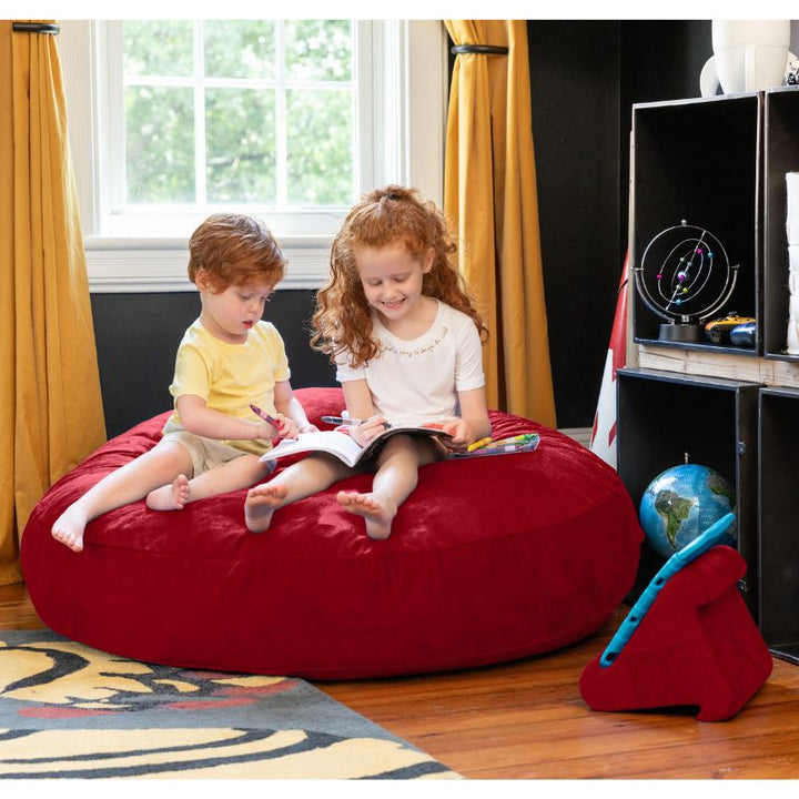Two children reading together on a red Jaxx Cocoon 4ft kids bean bag chair, a bold sensory crash pad for kids
