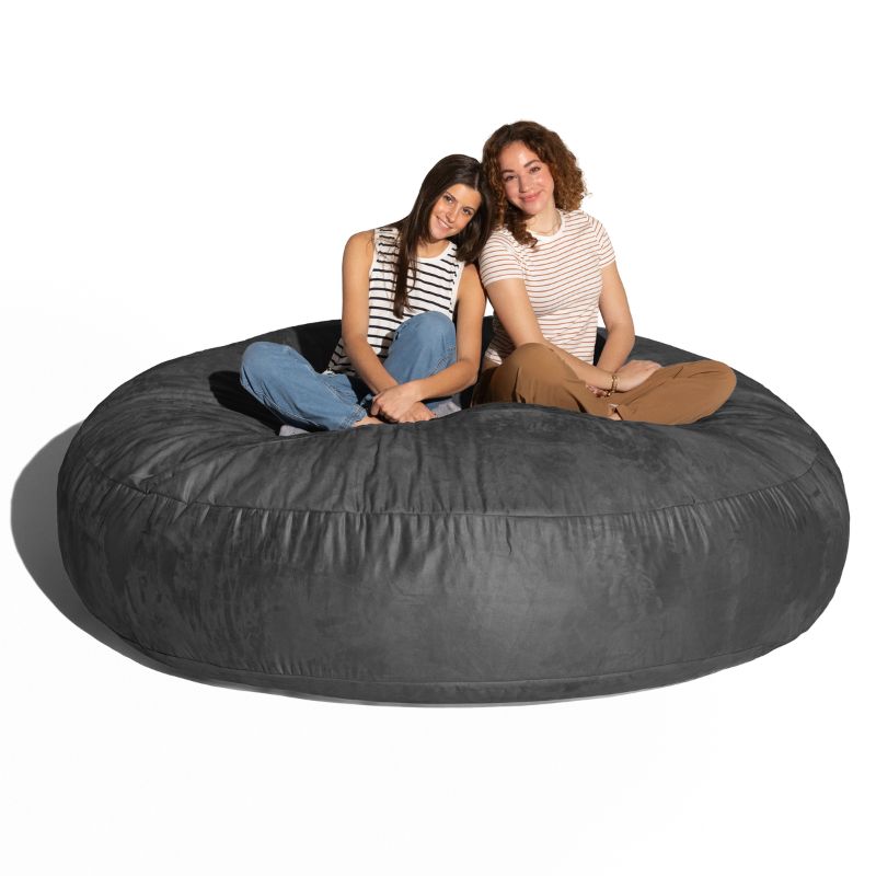Two adults sitting together on a black Jaxx Cocoon 6ft bean bag chair, an oversized sensory lounger