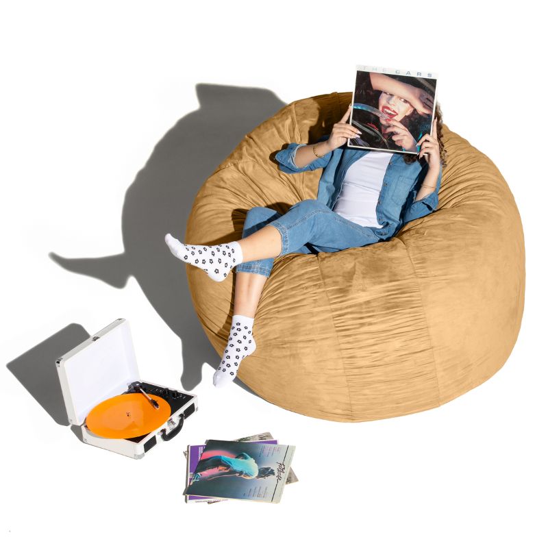 A woman relaxing with records on a camel Jaxx Cocoon 6ft bean bag chair, a giant deep pressure crash pad