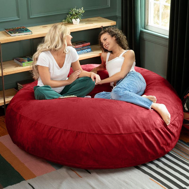 Two friends sitting together on a cinnabar Jaxx Cocoon 6ft bean bag chair, a bold oversized sensory seat
