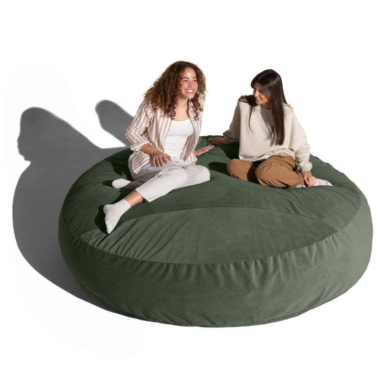 Two friends sitting and chatting on a green Jaxx Cocoon 7ft XL bean bag chair, an extra-large sensory lounger