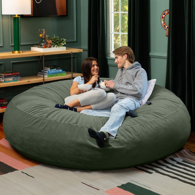 Two friends sharing snacks on a green Jaxx Cocoon 7ft XL bean bag chair, an extra-large sensory crash pad