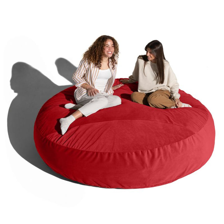 Two friends sitting and chatting on a merlot Jaxx Cocoon 7ft XL bean bag chair, a bold giant sensory lounger